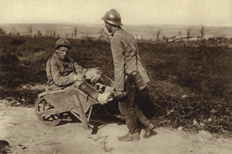 Fången fransk soldat som transporterade sin skadade kamrat i en skottkärra, första världskriget av Photographer German