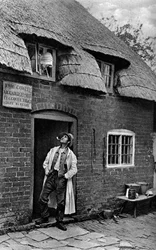 En man röker pipa utanför en butik, Worcestershire, c1922.