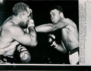 Unge Cassius Clay träffar veteranen Archie Moore med en vänster i första ronden av matchen i Los Angeles