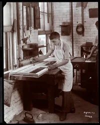 En ung man som arbetar i Harrington Piano Co.-fabriken, 1907 (silvergelatintryck)