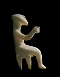 Kykladisk konst: "Figurin sittande på en pall". Marmoridol med inläggningar av ockra. Kykladisk civilisation (-3200 till -2000). Höjd 15.2 cm. Aten, Nationella arkeologiska museet (inv. 3910)