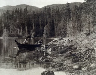 Amerikanska indianer som paddlar kanot på stranden av nootka