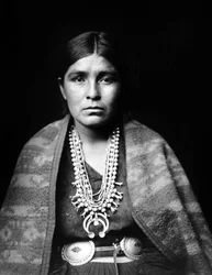 Navajokvinna som bär silverhalsband med squashblommor, conchobälte, filt draperad över axlarna, ca. 1904, foto Edward S. Curtis