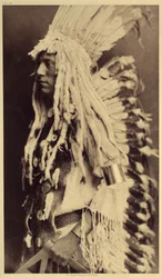 Gammal person, Piegan. Unga män missar inte något tillfälle av offentliga festligheter för att ta på sig kläderna till sin krigarfar. Foto taget från volym 6 av uppslagsverket publicerat av Edward S. Curtis (1868-1952) om indianerna i Nordamerika, med en f