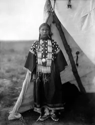 Rosa Lame Dog, Dakota-kvinna som står vid dörröppningen till tipi, ca. 1905, foto Edward S. Curtis