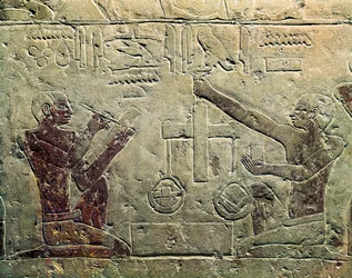 Basrelief som representerar en köpman och en kund: en av figurerna använder en skala medan den andra gör anteckningar, ca 2465-2323 f.Kr.