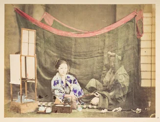 Japanskt par på sin fritid, Studiotablå av en ung japansk kvinna, sittande med tekokningshinder runt sig och räcker en pipa till en mansfigur som sitter bakom henne, skyddad av ett linnemyggnät,   Fotograf: Okänd  Lucas samling: