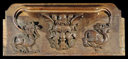 En misericord som visar tre mänskliga ansikten flankerade av monster, New College Chapel, Oxford, sent 1300-tal (trä)