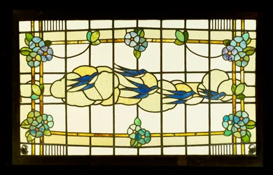Arts and Crafts panel av en grupp svalor före moln i en kant av stiliserade blomhuvuden (blyat och målat glas)