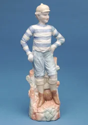 Bisquefigur av en pojkefotbollsspelare i blå- och vitrandigt kit, ca 1890-tal (keramik)