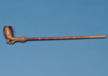 Kopplingsrör med bambuskaft och snidad stövel som sparkar en boll under (lera)