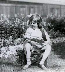 En ung flicka Betty som håller en östlig indigorm när hon sitter på en läderkoffert, London Zoo, 1924