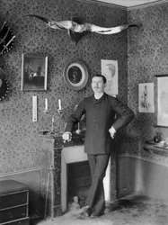 Porträtt av en ung man som poserar i vardagsrummet och dekorerar klostret Septfontaines, nära Bourmont en Haute Marne. Fotografi sent 1800-tal. Ducos samling.