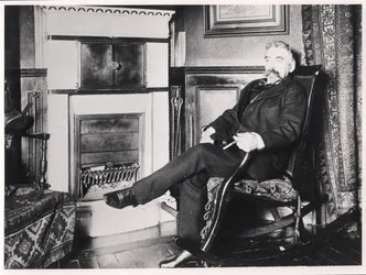 Stephane Mallarme (1842-98) sittande vid den öppna spisen i sitt hem på Rue de Rome, Paris