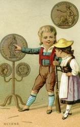 Schweizisk pojke och flicka som beundrar en visning av schweiziska franc, från en serie reklamkort på valutor i olika länder, publicerade i Paris av Baster & Vieillemard för användning av chokladprod.