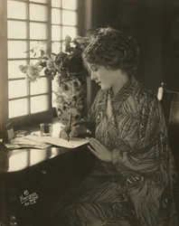 Mary Pickford, iklädd kimono, skriver vid ett skrivbord, ca 1918 (s/v foto)