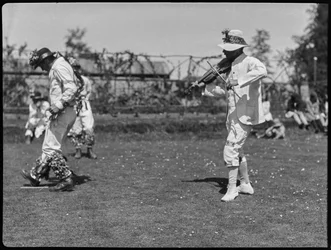 En medlem av Bampton Morris-truppen uppträder i en "Pipe Dance", ackompanjerad av en fiolspelare