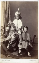 Ung flicka med hatt på gunghäst med en annan tjej stående, 1860-tal (albumintryck)