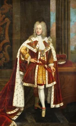 Porträtt av kung George II när prinsen av Wales, i full längd, iklädd statsdräkt och krage av strumpebandsorden, med sitt svärd i sin vänstra hand och sin krona på ett bord bredvid honom, i en interiör,