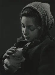 Flicka håller en vit kattunge i famnen. Tidigt 1950-tal