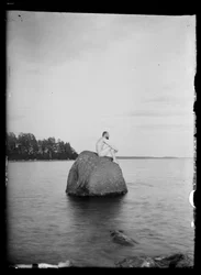 Hugo Simberg sittande på en klippa, Essaari och Suonionsaari i bakgrunden