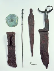 Uppifrån och ned: kniv, spjutspets, fiskkrok, klädnål, bälteskiva och yxa, alla funna i mansgravar i Hallstatt, järnåldern
