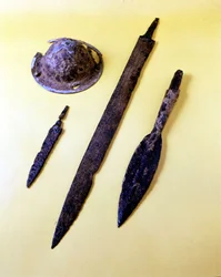 Vapen från en lombardisk krigare: sköldparaply, dolk, svärd och spjutspets. Cividale del Friulis museum.