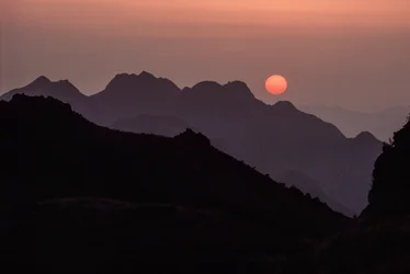 En lysande karmosinröd, orange sol går ner över bergskedjan Yan Shan. Shanhaiguan-passet, H...