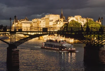 Mörka moln hänger över oss när en båt passerar under Pont des Arts. Floden Seine, Pa...