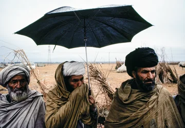 Pakistanska män med paraply och traditionella kläder