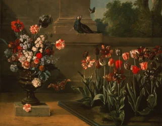 Tulpanbädd och vas med blommor vid foten av en vägg