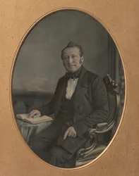 Sittande man som pekar på en passage i en öppen bok, 1850-talet.