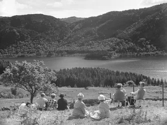 Grupp av människor som sitter på gräs eller solstolar och tittar på en utsikt över Thirlmere