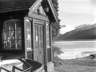 Vy över en entré till "Anglers Hotel", sjö och fjäll till höger i bild