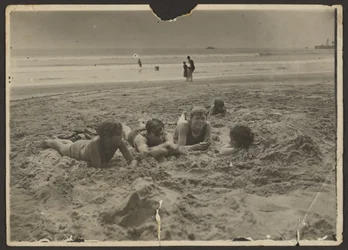 [Barn som ligger i sanden på stranden]