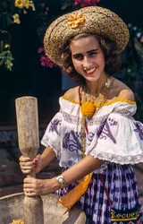 Kvinna i stråhatt i Panama som maler med en traditionell mortel och mortelstöt.