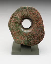 Öronbloss med inskuren bild av huvudfågelguden, ca 300-500 (jadeit)