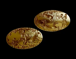 Mykensk konst: två guldsigill med framställningen av en jaktscen på en stridsvagn och en krigare som möter tre motståndare. 1550-1100 f.Kr. från grav IV i Mykene. Nationella arkeologiska museet i Aten (inv. 240 och 241)