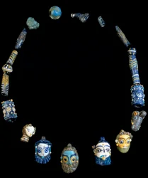 Halsband av glaspasta med hängen som föreställer skäggiga huvuden, ursprungligen från Olbia, nu bevarat på Nationella arkeologiska museet i Cagliari