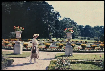 Kvinna promenerar i trädgården vid Bagatelle, Paris, ca 1920 (foto)