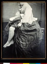 Grevinnan Verasis de Castiglione, född Virginia Oldoini, sittande på ett bord. Grevinnan lyfter sin klänning för att blotta sina ben och fötter. Silvergelatinbromidprov, 1863, Paris, Musée d