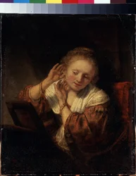 Ung kvinna som försöker på örhängen. Ung kvinna som försöker på örhängen. Målning av Harmenszoon van Rijn känd som Rembrandt (1606-1669)