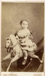 Ung flicka sitter på en gunghäst, 1860-tal (albumintryck)