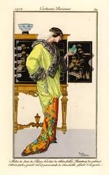 Kvinna i sidenklänning med chinchillakant, citrongrön sammetscape med chinchillakrage och muddar, håller i en buddha i jade. Kinesiskt skåp i bakgrunden. Robe de soie de chine bordee de chinchilla, manteau de velours citron vert a grand col et parement