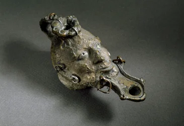Romersk konst: oljelampa i brons i form av ett ansikte. 1:a eller 2:a århundradet e.Kr. Spaniens museum i Ampurias (Empurias)