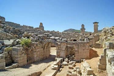 Utsikt genom den välvda ingången till Xanthos-teatern in i orkestergropen, med pelare och harpygrav, Xanthos, Turkiet (foto)