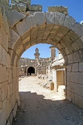 Utsikt genom den välvda ingången till Xanthos-teatern in i orkestergropen, med pelare och harpygrav, Xanthos, Turkiet (foto)