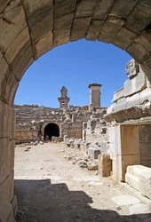 Utsikt genom den välvda ingången till Xanthos-teatern in i orkestergropen, med pelare och harpygrav, Xanthos, Turkiet (foto)