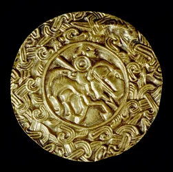 Medeltidens arkeologi (medeltiden). Barbarisk konst i Lombardiet: guldskiva. I centrum står ett helgon till häst med spjut och runt djurmotiv. Lombardkonst, ca 600. Dim: 47 cm Italien, Cividale del Friuli, Arkeologiska museet