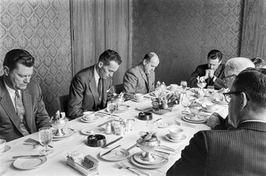 Affärsmän ber innan de börjar äta lunch på ett insamlingsmöte i en kyrka